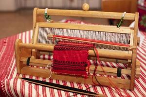 Spinning machine. An old wooden spinning wheel on a table with an embroidered shirt. photo