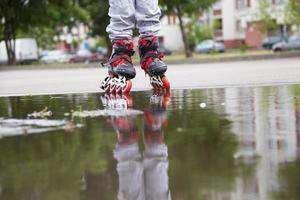 Roller skating. Legs in roller skates ride through a puddle. photo