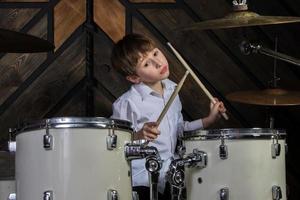 The boy learns to play the drums. The child behind the drum kit. photo