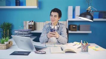 el joven hombre quien sonrisas y envía un mensaje a el teléfono piensa acerca de qué a escribir y cuando un idea viene a su mente, él devoluciones a el teléfono de nuevo. joven hombre enviar mensajes de texto video