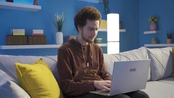 jong Mens sms'en met mensen gebruik makend van laptop en lachend. de gezicht van de jong Mens wie is sms'en met de andere partij van de laptop Bij huis is glimlachen en gelukkig. video