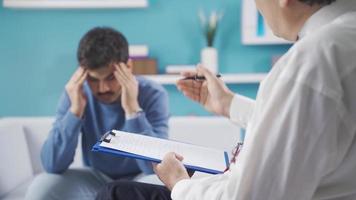 Sad and depressed young man talking to therapist, Getting psychological support. The psychotherapist takes notes and listens while the patient with psychological problems talks about their problems. video