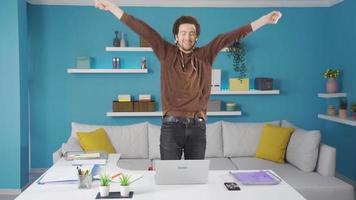 The university student gets up from his seat while looking at the laptop and dances in front of what he sees on the screen. video