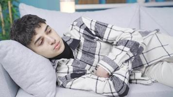 Young man stretching on the sofa is thoughtful and troubled. Depressed teenager is lying on the sofa, thinking. They have problems. video