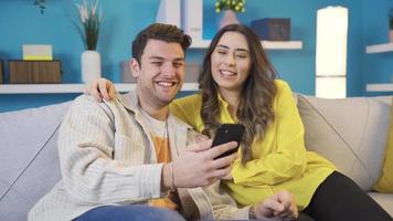 Happy couple resting on sofa in living room, having fun. Happy husband and wife enjoying spending time with each other while sitting on sofa and relaxing. Smile, Have Fun. video