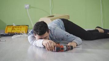 The clumsy young man who does not receive job security has a work accident at home, faints, falls to the ground. Clumsy and dexterous young man falls from chair while doing home repairs. video