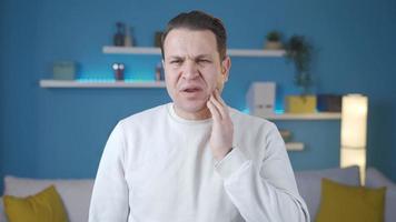 uomo sofferenza a partire dal mal di denti a casa. mal di denti. il uomo è Tenere il suo bocca perché lui ha un' mal di denti, in piedi a casa. video