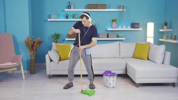 The man who cleans his house while dancing, in a good mood. Happy man listening to music, dancing and happily busy cleaning his house. video