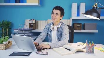 Student looking at camera with disgust while looking at laptop makes a negative gesture with his hand. video