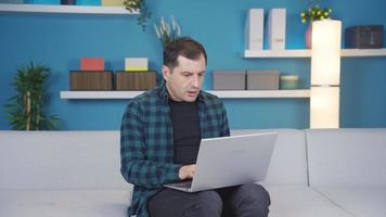hombre mecanografía o trabajando utilizando ordenador portátil es asombrado y decepcionado acerca de el Noticias y mensajes él ve video