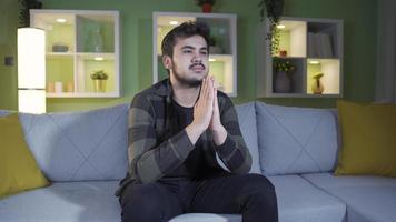cristiano joven hombre Orando a Dios a hogar. contento joven hombre cristiano religioso Orando, deseando bien a dios. video