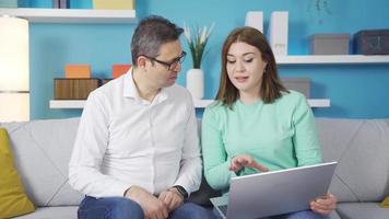 Young girl showing laptop to dad. It explains its use. Technology use. Teenage girl talking to her father about using laptop. The father listens carefully to his daughter. They are happy. video