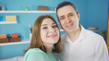 padre y hija tomando selfie con teléfono. de cerca de padre y hija mirando a cámara. ellos actitud para autofotos ellos son divertido y contento. video