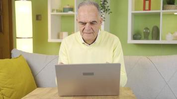 At home, the old man does not use a laptop, he does his work on the Internet, he has difficulties. The old man who uses the laptop to do his work at home cannot use the laptop and understand it. video