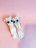 Baby socks with eyes and smile on pink background photo