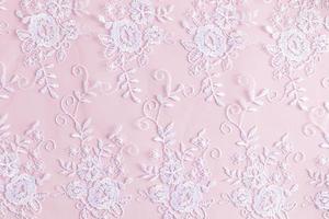 elegant background with a lace white pattern on pink satin. delicate background texture. photo