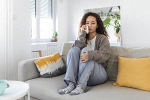 Unhappy young Asian woman crying alone close up, depressed girl sitting on couch at home, health problem or thinking about bad relationships, break up with boyfriend, divorce photo