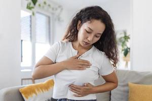 Young Asian woman palpating her breast by herself that she concern about breast cancer. Healthcare and breast cancer concept photo