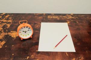 blanco papel, un reloj y un lápiz foto