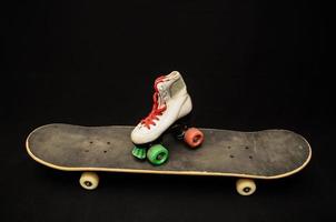 Skateboard and roller skate on black background photo