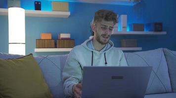 bezorgd en onzeker ontmoedigd jong Mens gebruik makend van laptop Bij huis negatief jong Mens met pessimistisch gedachte is gebruik makend van laptop in een bezorgd en in paniek staat. video