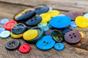 un montón de vistoso botones para ropa en de madera antecedentes. foto