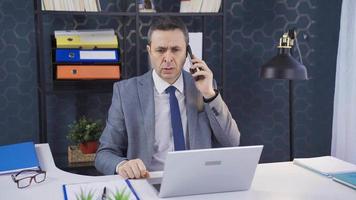 maduro hombre trabajando en oficina hablando en teléfono acerca de negocio problemas, frustrado, asombrado. video