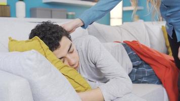 Love of Mother. Mother covering her son who fell asleep on the sofa with a blanket. The mother covers her only son with a blanket and kisses him. video