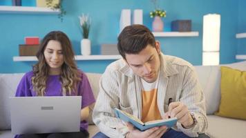 Happy and cute couple working from home sharing ideas with each other, brainstorming. The couple working on something is indecisive, they consult each other, cooperate. video