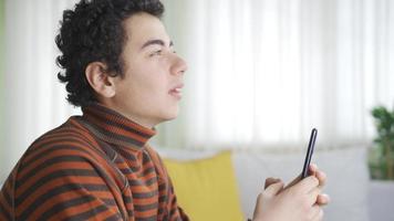 telefon Beroende pojke spenderar för mycket tid på Hem med hans smartphone. tech Beroende pojke ser och använder sig av hans smartphone för mycket på Hem. video