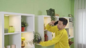 Clumsy young man talking on phone at home drops flower pot on floor. The unfortunate teenager clumsily drops the flower pot while talking on the phone at home. video