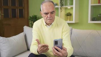 vedendo immorale e fastidioso immagini nel il Casa, il vecchio uomo prende arrabbiato. pensionato vecchio uomo vede indecente e immorale immagini mentre guardare a il suo smartphone a casa e si blocca su nel la rabbia. video