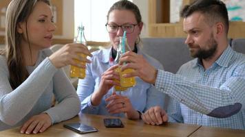 Trois copains asseoir dans une café, boisson jus et avoir amusement communicant video