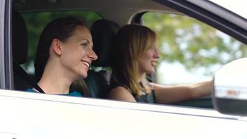 dos joven mujer paseo en un coche y tener divertida. lento movimiento video