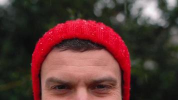 Porträt von ein Mann im ein rot Deckel im schneebedeckt Wetter draußen video