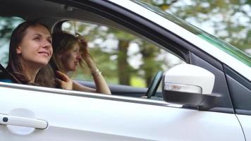 zwei jung Frauen Reiten im ein Auto und haben Spaß. schleppend Bewegung video