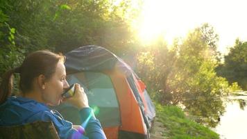 femme femme est en buvant thé dans une tente et à la recherche à le Feu dans de face de sa video