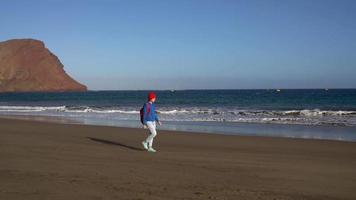 aktiv Wanderer Frau Spaziergänge auf das Strand zu das Wasser. kaukasisch jung Frau mit Rucksack auf Teneriffa, Kanarienvogel Inseln video