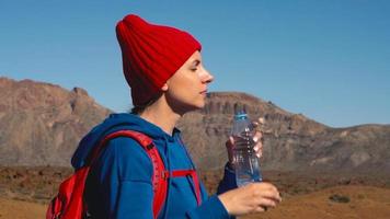 escursioni a piedi donna potabile acqua dopo escursione su teide, tenerife. caucasico femmina turista su tenerife, canarino isole video