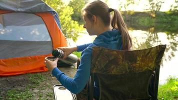 vrouw vrouw is drinken thee in een tent en op zoek Bij de brand in voorkant van haar video