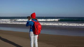 aktiv Wanderer Frau Spaziergänge auf das Strand zu das Wasser. kaukasisch jung Frau mit Rucksack auf Teneriffa, Kanarienvogel Inseln video