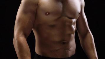 homem mostra uma muscular Forte corpo fechar-se em uma Preto fundo. abdominal músculos tenso video