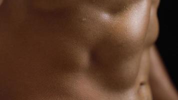 Man shows a muscular strong body close-up on a black background. Abdominal muscles tense video