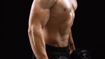 Man is doing exercises with a barbell, training on a black background in the studio. Half body in frame video