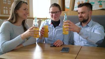 Trois copains asseoir dans une café, boisson jus et avoir amusement communicant video