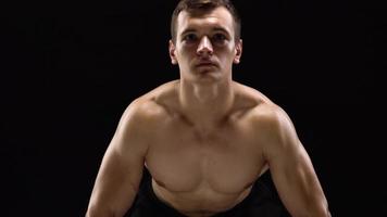 Man is doing exercises with a barbell, training on a black background in the studio. Half body in frame video