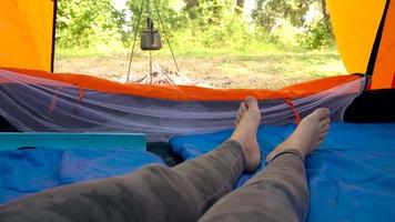 donna è potabile tè nel un' tenda e guardare a il fuoco nel davanti di sua video