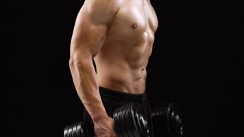 Man is doing exercises with a barbell, training on a black background in the studio. Half body in frame video