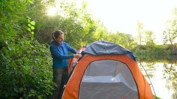 Woman is putting a tourist tent in the forest video