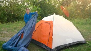 Woman is putting a tourist tent in the forest video